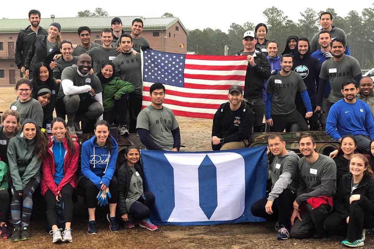 Members of Operation Blue Devil grouped around American flag and Duke flag