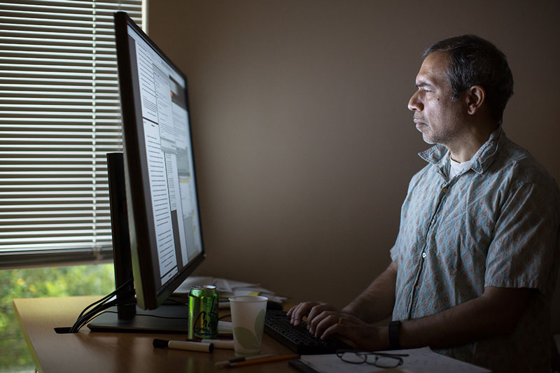 Professor Ashish Arora performing research on his computer in his office