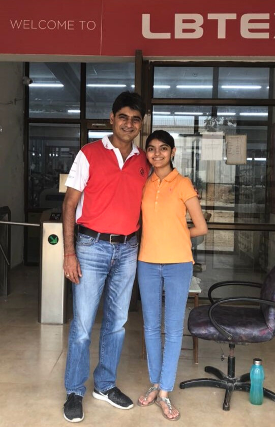 Anoushka standing side by side with her father in front of their company sign.