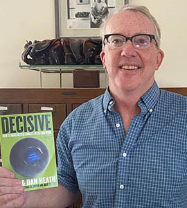 Professor Rick Larrick holding up a copy of Decisive